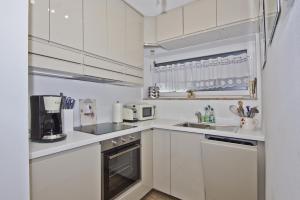 een witte keuken met witte kasten en apparaten bij hafennahe Ferienwohnung im Erdgeschoss mit Terrasse - Haus Hafenkieker FeWo 02 in Lauterbach