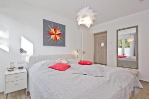 een witte slaapkamer met een groot bed met rode kussens bij hafennahe Ferienwohnung im Erdgeschoss mit Terrasse - Haus Hafenkieker FeWo 02 in Lauterbach