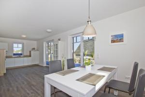 a dining room and kitchen with a white table and chairs at gemütliche Ferienwohnung mit Terrasse und Garten - Ferienhaus Zaunkönig FeWo EG in Groß Zicker