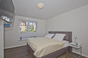 a white bedroom with a bed and a window at gemütliche Ferienwohnung mit Terrasse und Garten - Ferienhaus Zaunkönig FeWo EG in Groß Zicker