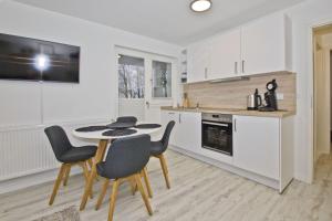 cocina con armarios blancos, mesa y sillas en moderne Ferienwohnung mit Kamin, Balkon - Ferienresidenz Zwei Bodden FeWo111, en Lietzow