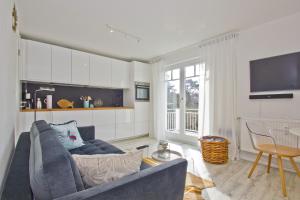 a living room with a blue couch and a tv at moderne 2-Raum-Ferienwohnung mit Balkon - Ferienresidenz Zwei Bodden FeWo 1-4 in Lietzow