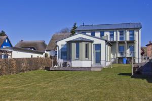 ein weißes Haus mit blauen Fenstern und einem Hof in der Unterkunft Balkon mit Meerblick, ruhige Lage - Ferienhaus Distelfink FeWo 01 in Groß Zicker