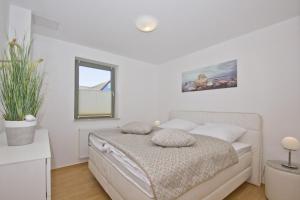 ein weißes Schlafzimmer mit einem Bett und einem Fenster in der Unterkunft Balkon mit Meerblick, ruhige Lage - Ferienhaus Distelfink FeWo 01 in Groß Zicker