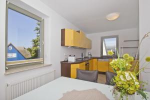 eine Küche mit gelben Schränken und einem großen Fenster in der Unterkunft Balkon mit Meerblick, ruhige Lage - Ferienhaus Distelfink FeWo 01 in Groß Zicker