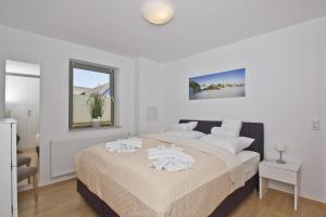 ein weißes Schlafzimmer mit einem großen Bett mit weißen Kissen in der Unterkunft Balkon mit Meerblick, ruhige Lage - Ferienhaus Distelfink FeWo 01 in Groß Zicker
