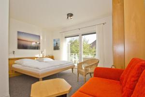 1 dormitorio con cama, sofá y ventana en nur 100 m zum Strand, FeWo mit Balkon und Terrasse - App Eldena FeWo 04, en Lobbe