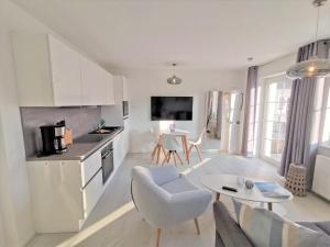 a kitchen and living room with a couch and a table at moderne Ferienwohnung mit eigener Terrasse - Haus Inselwind FeWo MEERhafen in Groß Zicker +12 photos