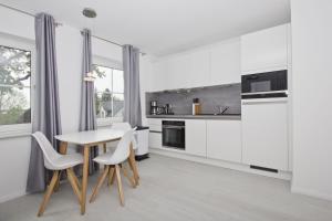 a kitchen with white cabinets and a table and chairs at moderne Ferienwohnung mit Gartennutzung - Haus Inselwind FeWo MEERbucht in Groß Zicker +13 photos