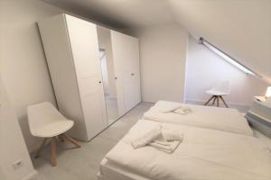 a white bedroom with two beds and a mirror at Ferienwohnung mit Dachterrasse und Meerblick - Haus Inselwind FeWo MEERwasser in Groß Zicker