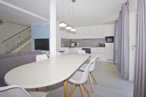 a kitchen and dining room with a white table and chairs at Ferienwohnung mit Balkon und Gartennutzung - Haus Inselwind FeWo MEERurlaub in Groß Zicker