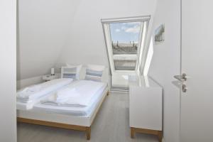 a white bedroom with a bed and a window at Ferienwohnung mit Balkon und Gartennutzung - Haus Inselwind FeWo MEERurlaub in Groß Zicker