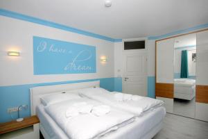 a white bed in a room with a blue wall at strandnah, Balkon, Meerblick, Sauna, gratis Nutzung vom AHOI Erlebnisbad und Sauna in Sellin - Beach House Palstek in Göhren +25 photos