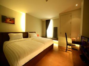 a bedroom with a bed and a desk and a television at Silom One in Bangkok