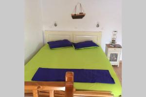 a green bed with blue pillows in a room at The Red-Fish House in Astypalaia Town