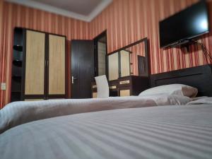 a bedroom with two beds and a flat screen tv at Chveni sakhli in Tbilisi City