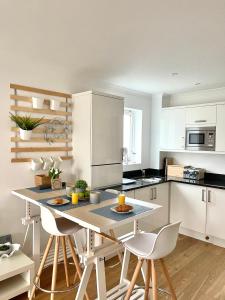 a kitchen with white cabinets and a table with chairs at Luna Beach - Luxury Carbis Bay Apartment With Parking in Carbis Bay