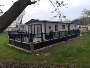 una casa con una valla negra en un patio en Bluebell Lodge, en South Cerney