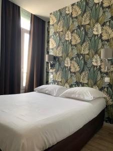 1 dormitorio con 1 cama grande y papel pintado con motivos florales en Le Royalty, en Angers