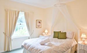 a bedroom with a white bed with a window at Encounter Hideaway Cottages in Encounter Bay