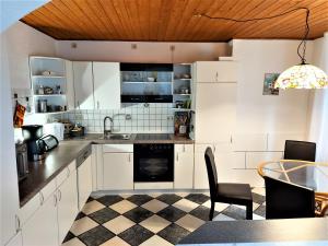 a kitchen with white cabinets and a checkered floor at Apartment de luxe 73 qm mit 3 Zimmer und Terrasse in Einhausen