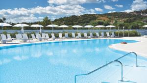 une grande piscine avec des chaises longues et des parasols dans l'établissement Piccolo Hotel - Adults Only, à Porto Ottiolu