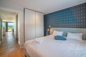 - une chambre avec un grand lit blanc et un mur bleu dans l'établissement Au bois du Sart-Tilman, à Sur le Mont