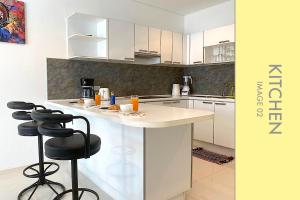 a kitchen with white cabinets and black bar stools at Stylish Condo w. Pool View 2F in Kamala Beach