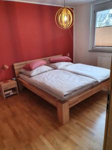 sypialnia z 2 łóżkami i czerwoną ścianą w obiekcie Ferienwohnung Lavendel w mieście Lahr/Schwarzwald