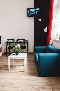 a living room with a couch and a table with flowers at SouvenirAppart Wilenska in Bydgoszcz