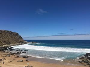 a beach with people on the sand and the ocean at Encounter Hideaway Cottages in Encounter Bay
