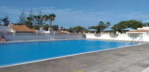 a large blue swimming pool with chairs and umbrellas at La graciosa in Costa Del Silencio