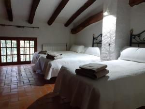 1 Schlafzimmer mit 2 Betten und weißer Bettwäsche in der Unterkunft Molí dels Aubins in Cornudella de Montsant
