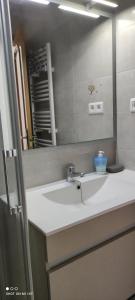 Un baño con un lavabo blanco y un espejo. en 1ere soleil levant, en Puerto Sagunto
