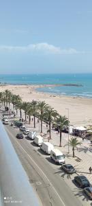 a beach with palm trees and cars parked on a street at 1ere soleil levant in Puerto de Sagunto