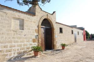un accès à un bâtiment en briques avec une porte dans l'établissement Baglio Bellavista, à Torre Nubia