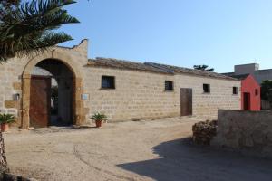un vieux bâtiment en briques avec une porte et un palmier dans l'établissement Baglio Bellavista, à Torre Nubia