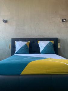 Cama con sábanas y almohadas azules y amarillas en L’ÉMERAUDE 4, en Châlons-en-Champagne