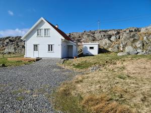 una casa bianca sul fianco di una collina rocciosa di Utsira Overnatting - Kvalvik a Utsira