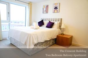 a white bedroom with a large bed and a window at Gunwharf Quays Apartments in Portsmouth