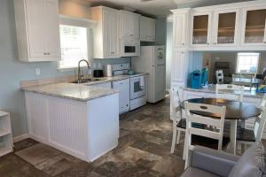 a kitchen with white cabinets and a table with chairs at Cozy Tiny Home Near Disney World & Orlando Parks! in Kissimmee