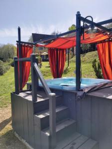 a hot tub on a deck with red curtains at BonBon Chambre d'hôtes in Saint-Julien-de-Lampon