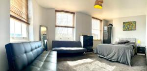 1 dormitorio con sofá, cama y ventanas en Camden Guest House Super king or Double Bedroom, en Londres