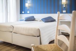 two beds in a room with blue walls at Hotel Capanna d'Oro in Lignano Sabbiadoro