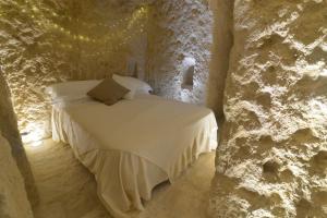 a bedroom with a bed in a stone wall at Grotta Gea Luxury Home con Piscina & Spa in Matera