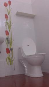 un aseo blanco en un baño con flores en la pared en Stay Well Ayurvedic Beach Resort, en Kovalam