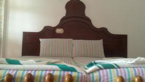 a bed with a wooden headboard and a striped blanket at Stay Well Ayurvedic Beach Resort in Kovalam