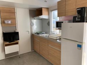 a kitchen with a white refrigerator and wooden cabinets at Mobil Home Canet plage in Canet-en-Roussillon