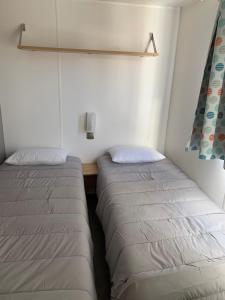 2 letti in una camera con pareti bianche di Mobil Home Canet plage a Canet-en-Roussillon