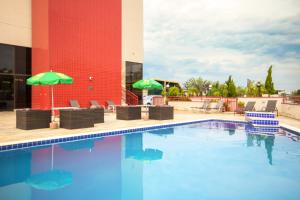 a pool with chairs and umbrellas next to a building at Hotel Dan Inn Campinas Anhanguera - By Nacional Inn in Campinas